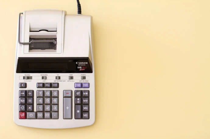 A grey printing calculator on a light yellow background